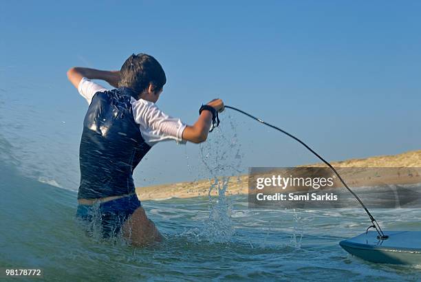boy (12) surfing and splashing in ocean waves - vista traseira a três quartos - fotografias e filmes do acervo