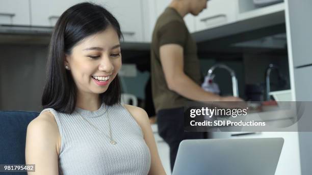 young woman smiles while using laptop - instagram husband stock pictures, royalty-free photos & images