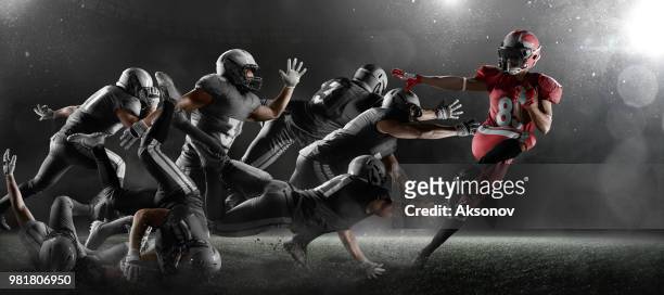 american football players in dark sport stadium - american football uniform stock pictures, royalty-free photos & images