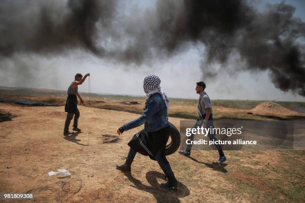 Dpatop - A Palestinian protester carries a tire to be burnt during clashes along the Israel-Gaza border in Jabalia, Gaza Strip, 06 April 2018....