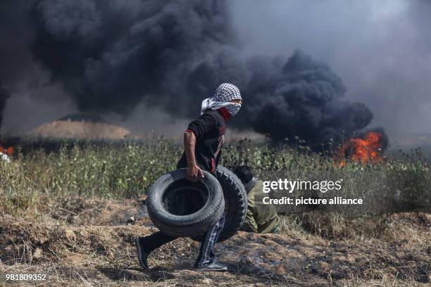 Dpatop - A Palestinian protester carries tires to be burned during clashes with Israeli forces along the Israeli-Gaza border in Jabalia, northern...