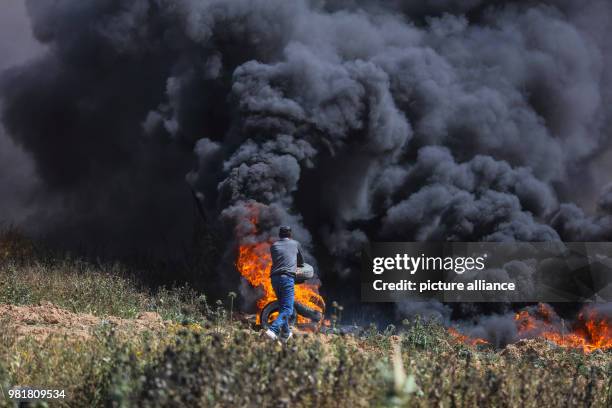 Dpatop - Palestinian protesters burn tires during clashes with Israeli forces along the Israeli-Gaza border in Jabalia, northern Gaza Strip, 06 April...