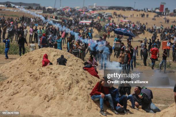 Palestinian protesters throw back a tear gas canister fired by Israeli security forces during clashes along the Israeli-Gaza border in Jabalia,...