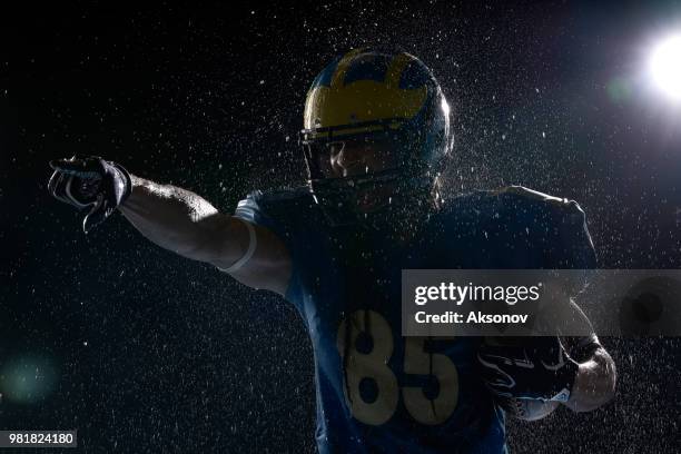 american football speler met bal in een water druppels op zwarte achtergrond. portret - aksonov stockfoto's en -beelden