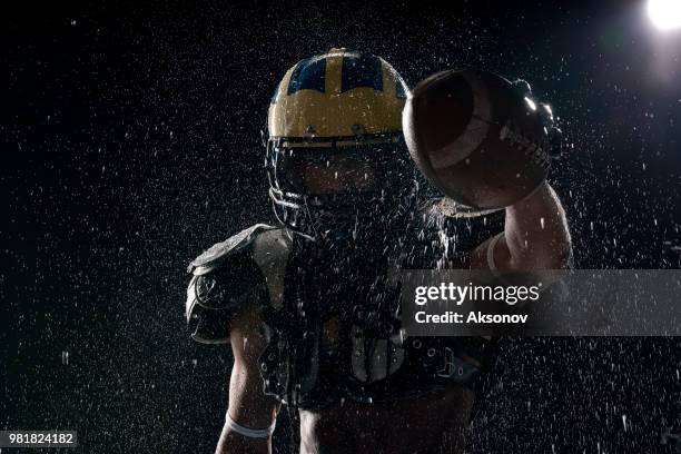 american football speler met bal in een water druppels op zwarte achtergrond. portret - aksonov stockfoto's en -beelden