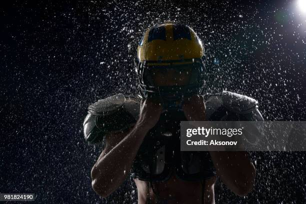 american football speler in een water druppels op zwarte achtergrond. portret - aksonov stockfoto's en -beelden