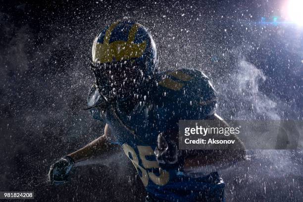 american football speler in een haze en regen op zwarte achtergrond. portret - aksonov stockfoto's en -beelden