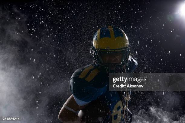 american football speler in een haze en regen op zwarte achtergrond. portret - aksonov stockfoto's en -beelden