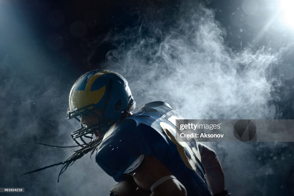 Giocatore di football americano in una foschia su sfondo nero. ritratto