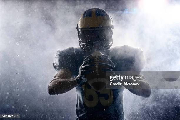 american footballspieler in einem dunst und regen auf schwarzem hintergrund. porträt - quarterback stock-fotos und bilder