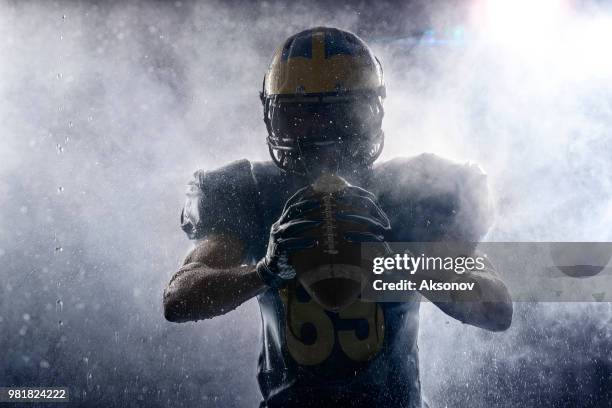 joueur de football américain dans une brume et pluie sur fond noir. portrait - joueur de football américain photos et images de collection