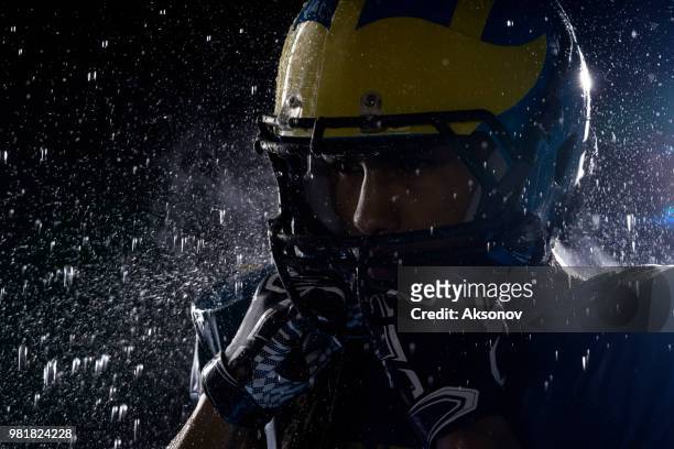 american football speler in een haze en regen op zwarte achtergrond. portret close-up - aksonov stockfoto's en -beelden