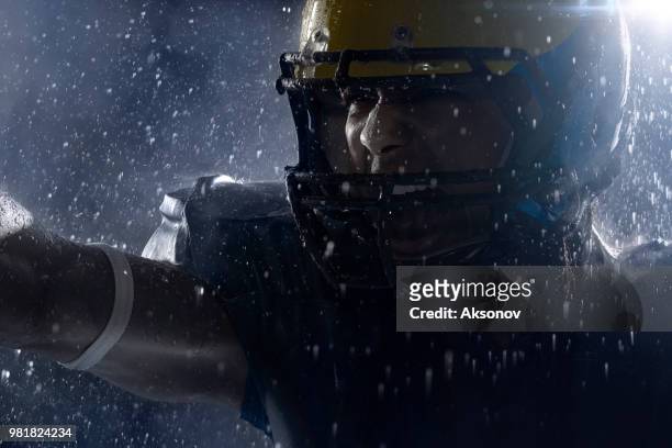 american football speler in een haze en regen op zwarte achtergrond. portret close-up - aksonov stockfoto's en -beelden
