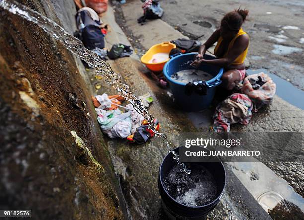 Woman washes clothes in the street in a populous neighbourhood in west Caracas on November 2, 2009. Residents of the Venezuelan capital face cuts in...