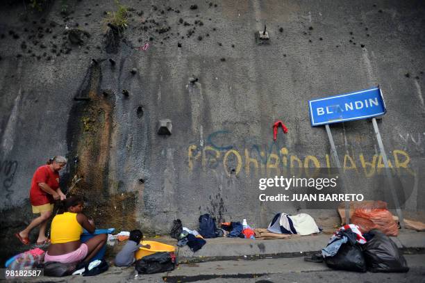 Woman washes clothes in a street drain in a populous neighbourhood in west Caracas on November 2, 2009. Residents of the Venezuelan capital face cuts...