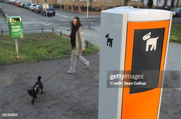 Woman walks her dog past a dispenser for paper dog excrement bags on April 1, 2010 in Berlin, Germany. The dispensers are operated by Berlin waste...