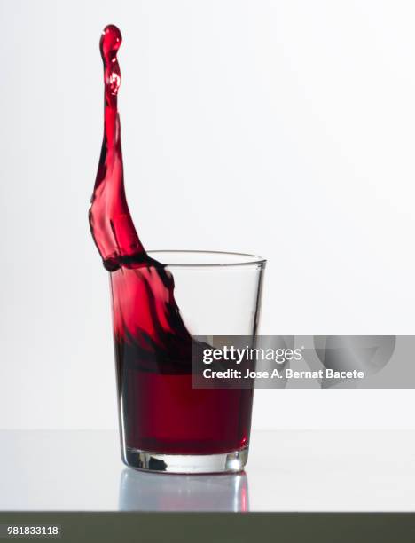 red wine splashing in glass in front of white background - fotografía de alta velocidad fotografías e imágenes de stock