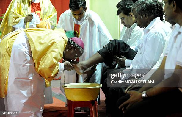 Indian Catholic Bishop of the Archdioecese of Hyderabad Reverend M. Joji kisses the feet of a parishioner during the evening mass of the Lord Supper...