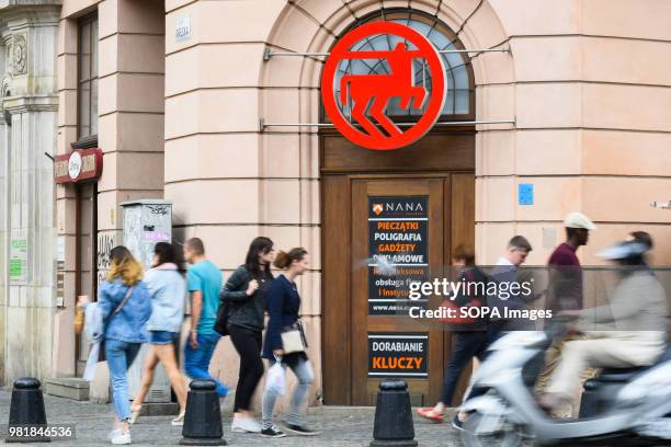 People walk by Rossmann logo in Krakow. Krakow is the second largest city in Poland and it is located in the southern part of the country.