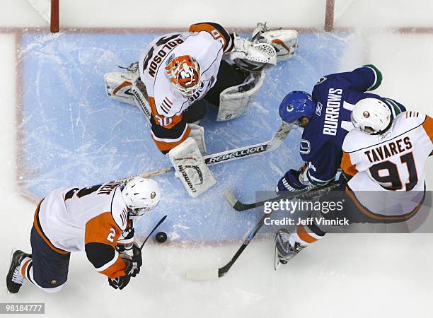 Mark Streit of the New York Islanders plays the puck as teammate John Tavares checks Alex Burrows of the Vancouver Canucks in front of Dwayne Roloson...