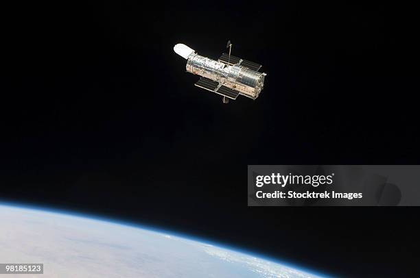 the hubble space telescope in orbit above earth. - hubble space telescope stock pictures, royalty-free photos & images