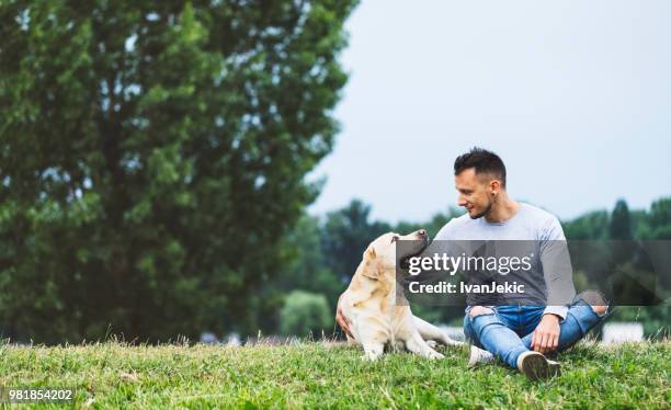 young man hugging his dog in nature - ivanjekic stock pictures, royalty-free photos & images