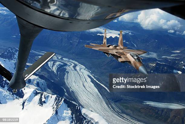 a u.s. air force f-15c eagle positioning itself behind a kc-135r stratotanker over alaska. - aerial refueling stock-fotos und bilder