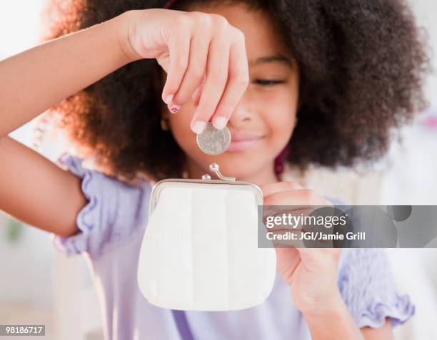 hispanic girl putting coin into purse - allowance stock pictures, royalty-free photos & images