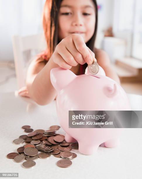 mixed race girl putting coin in piggy bank - allowance bildbanksfoton och bilder