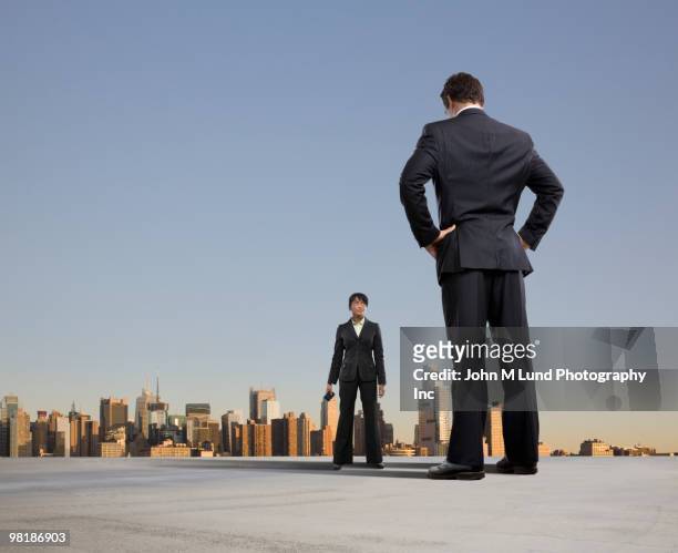 business people standing on urban rooftop - low angle view of two businessmen standing face to face outdoors stock pictures, royalty-free photos & images