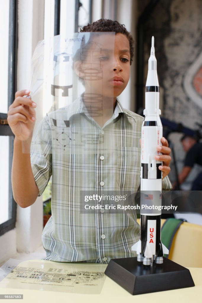 Mixed race boy building model rocket