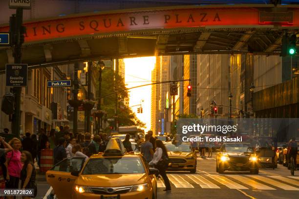 cars go through under the pershing square bridge and people cross the 42nd street while sun is setting for manhattanhenge new york u.s.a on 30 may 2018. the sky, buildings, street and people glows for the sunset. - pershing square stock pictures, royalty-free photos & images