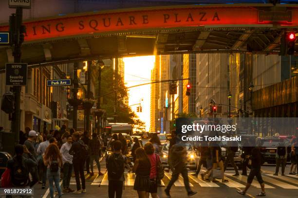 people cross under the pershing square bridge and cars run on the 42nd street while sun is setting for manhattanhenge new york u.s.a on 30 may 2018. the sky, buildings, street and people glows for the sunset. - pershing square stock pictures, royalty-free photos & images