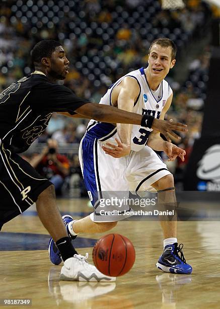 Jon Scheyer of the Duke Blue Devils passes the ball around E'Twaun Moore of the Purdue Boilermakers during the south regional semifinal of the 2010...