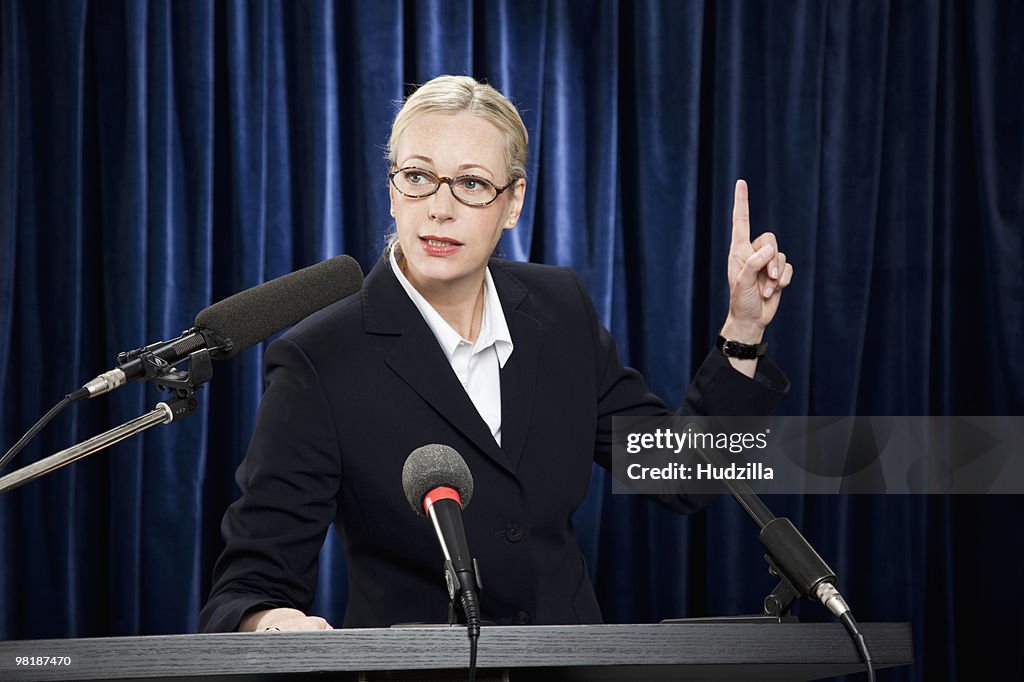 A woman in a suit speaking at a lectern