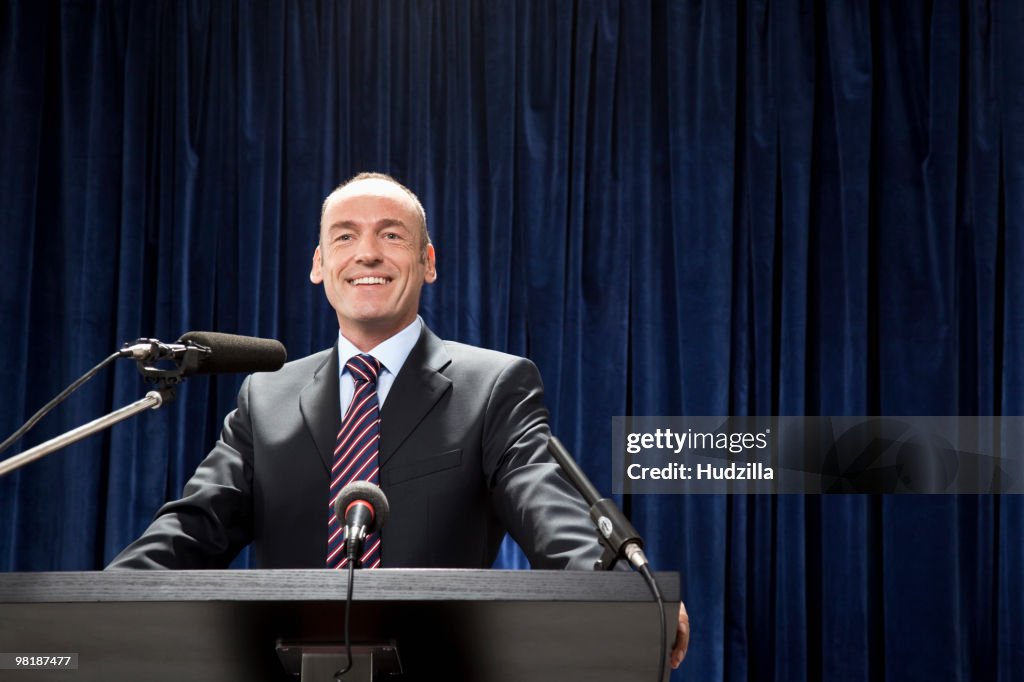 A man in a suit standing at a lectern