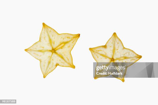 two slices of an organic carambola on a lightbox - carambola stock pictures, royalty-free photos & images