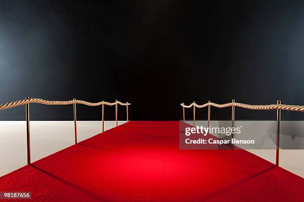 view down red carpet with rope barriers - red carpet stock-fotos und bilder