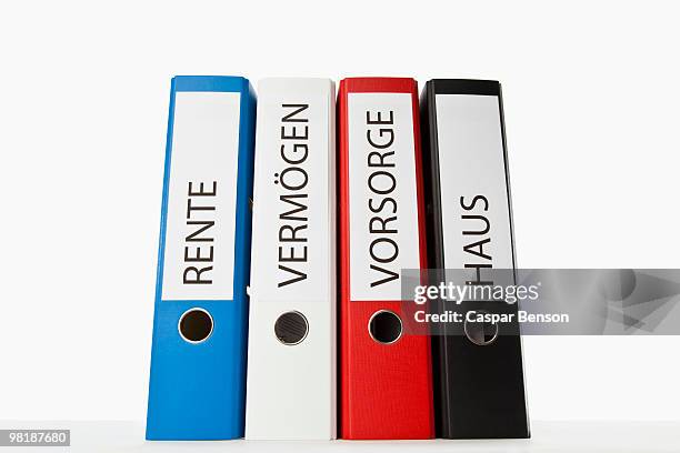 four colored ring binders with the german words for pension, retirement, finances, and house - binders stockfoto's en -beelden