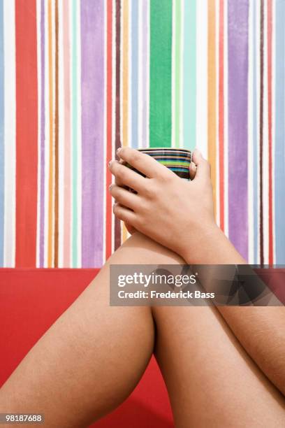 a woman holding a coffee mug, close-up of bent leg, arm and hand, side view - striped bass stock pictures, royalty-free photos & images