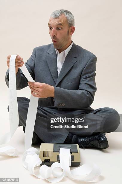 a shocked business man looking at printed receipts from a calculator - roll shirt stock pictures, royalty-free photos & images