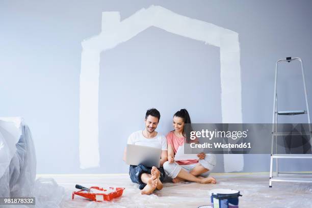 couple sitting in new apartment using laptop - open plan stockfoto's en -beelden