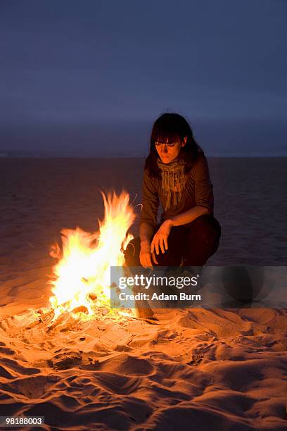 a woman staring into a fire burning on a beach - 9927 stock pictures, royalty-free photos & images