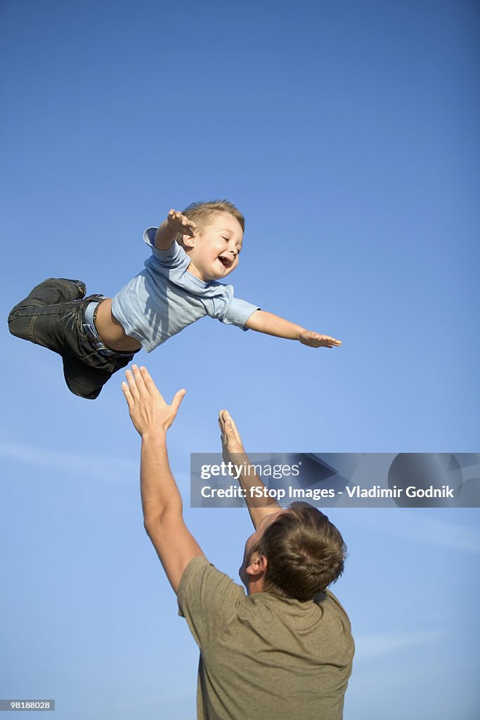 A man throwing a boy into the air