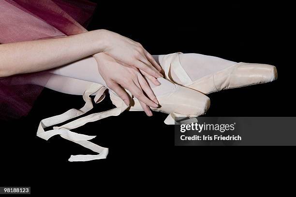 a ballet dancers hands posed gracefully with her feet in untied pointe shoes - scarpette-per-danza-classica foto e immagini stock