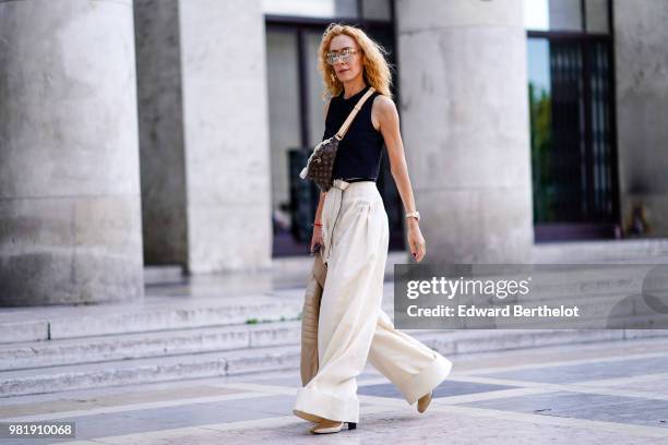 Elina Halimi wears a black tank top, white flared pants, a Vuitton bag, outside Juun J, during Paris Fashion Week - Menswear Spring-Summer 2019, on...