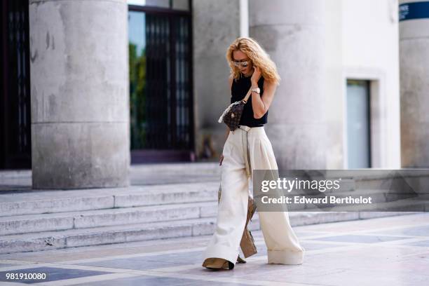 Elina Halimi wears a black tank top, white flared pants, a Vuitton bag, outside Juun J, during Paris Fashion Week - Menswear Spring-Summer 2019, on...