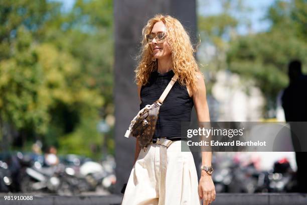 Elina Halimi wears a black tank top, white flared pants, a Vuitton bag, outside Juun J, during Paris Fashion Week - Menswear Spring-Summer 2019, on...