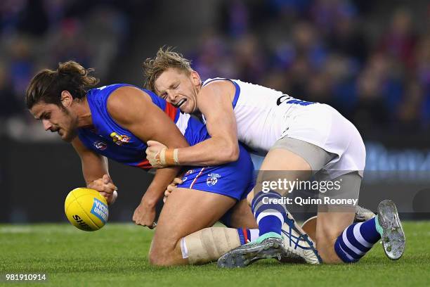 Tom Boyd of the Bulldogs handballs whilst being tackled by Jack Ziebell of the Kangaroos during the round 14 AFL match between the Western Bulldogs...