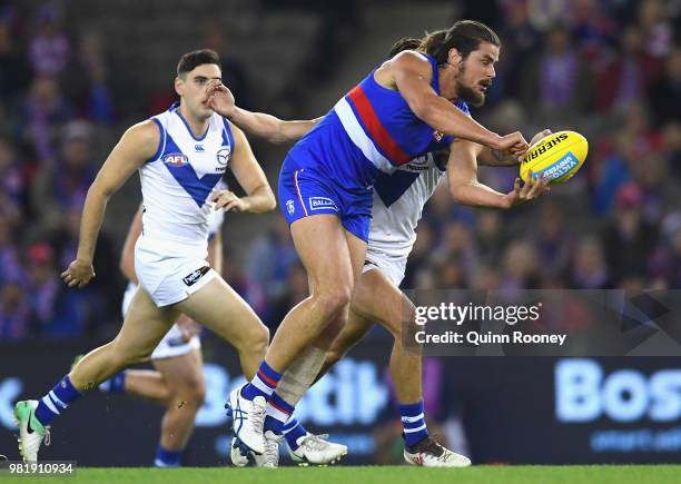 Tom Boyd of the Bulldogs handballs whilst being tackled during the round 14 AFL match between the Western Bulldogs and the North Melbourne Kangaroos...